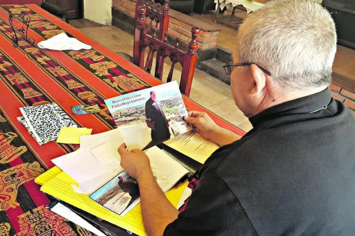 Un sacerdote observa, y muestra, una foto del padre Hugo Lamaison en Tafí.