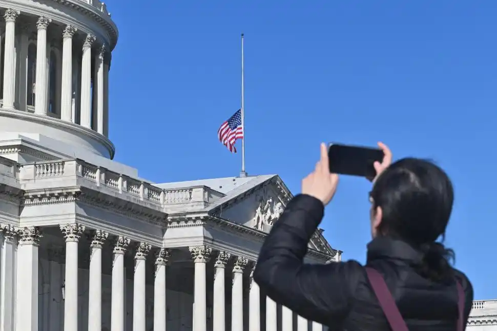 SÍMBOLO. Una mujer toma una foto de la bandera de Estados Unidos que ondea a media asta en el Capitolio en honor al ex presidente Carter.