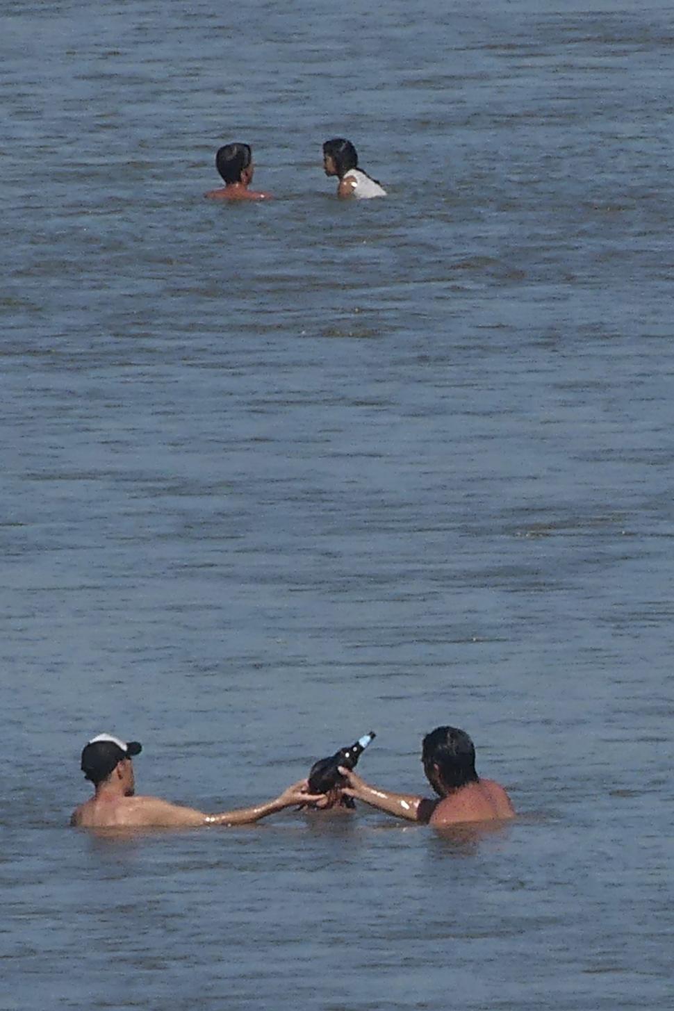COMO EN UN BAR. Dos amigos comparten una cerveza, mientras se refrescan en el río. la gaceta / fotos de osvaldo ripoll y franco vera