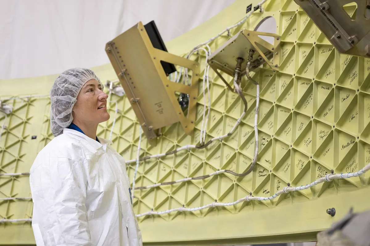 Christina Koch, astronauta de la NASA y especialista de la misión Artemis II, examina el adaptador de la etapa Orión, una estructura anular que conecta el cohete SLS de la agencia con la nave espacial Orión. Varios CubeSats se desplegarán desde el adaptador a la órbita terrestre alta durante el vuelo de prueba. NASA/Charles Beason