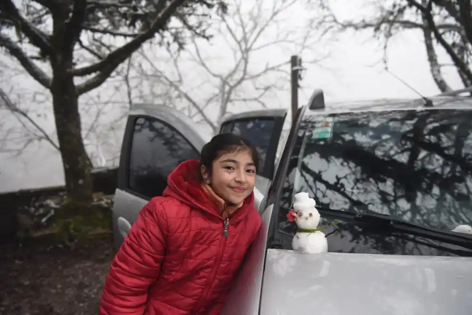 DE ROJO. La niña, de 11 años, adornó con una flor a tono de su abrigo el pequeño hombre de nieve que construyó con esmero.