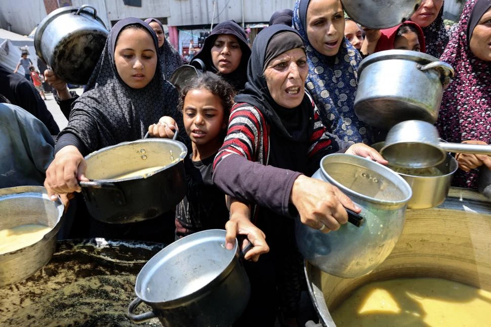 SOPA DE LENTEJAS. Refugiados palestinos ruegan por un poco de comida en los centros de distribución.