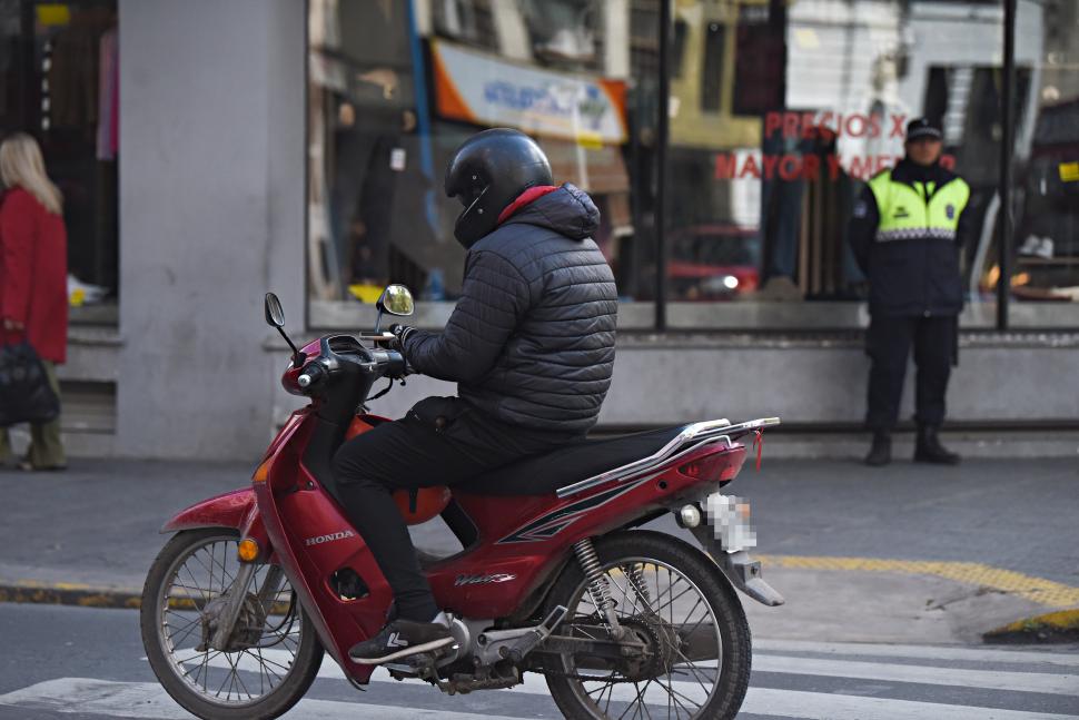 CONCENTRADO EN EL CELULAR. El motociclista pasa junto a un policía.