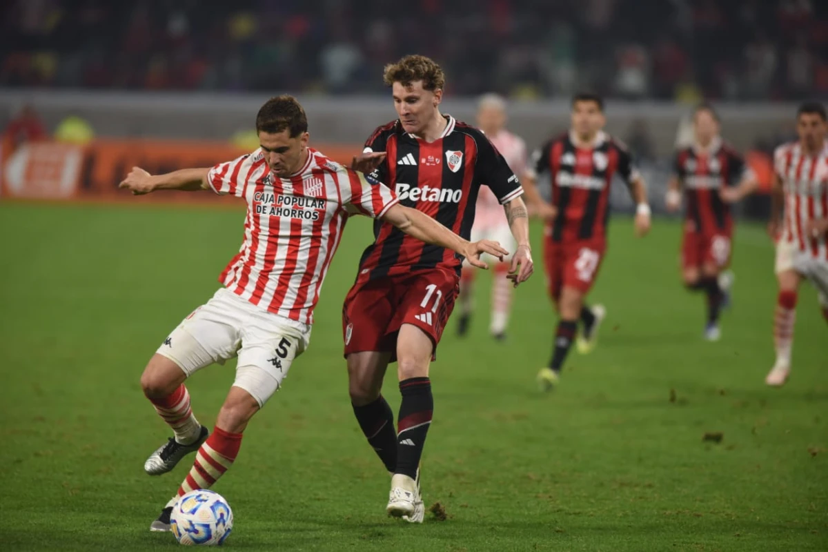 Matías García, de San Martín, cubre la pelota frente a la presión de Facundo Colidio, de River.