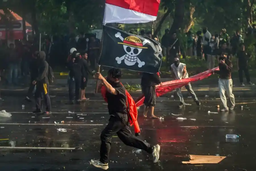 MÁS EJEMPLOS. Un manifestante lleva la bandera nacional de Indonesia y una bandera pirata del anime japonés One Piece durante una protesta frente a la residencia del gobernador en Surabaya, el 29 de agosto. / GETTY IMAGES