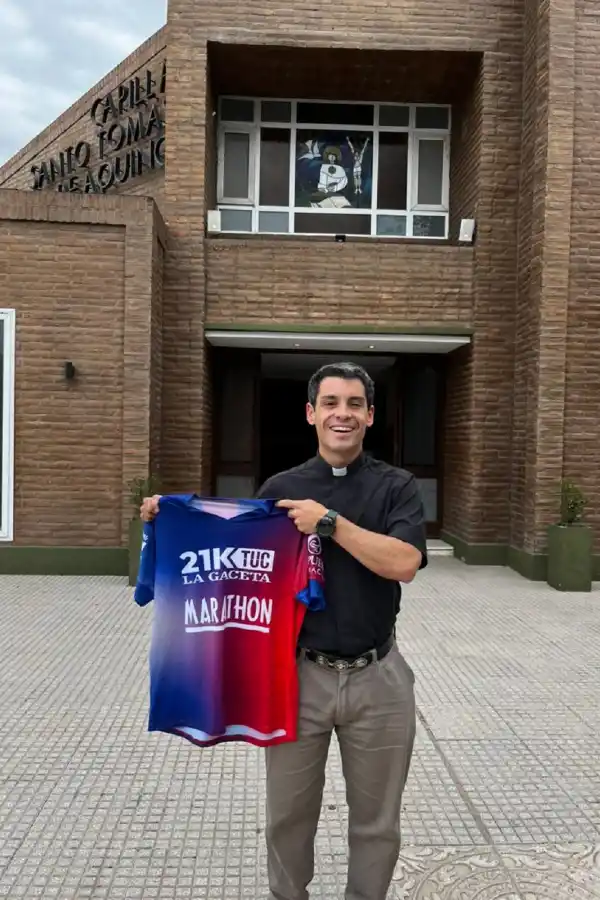 CON ORGULLO. El padre Larrosa posa con la camiseta de los 21k de LA GACETA frente a la Iglesia de la comunidad Fasta.