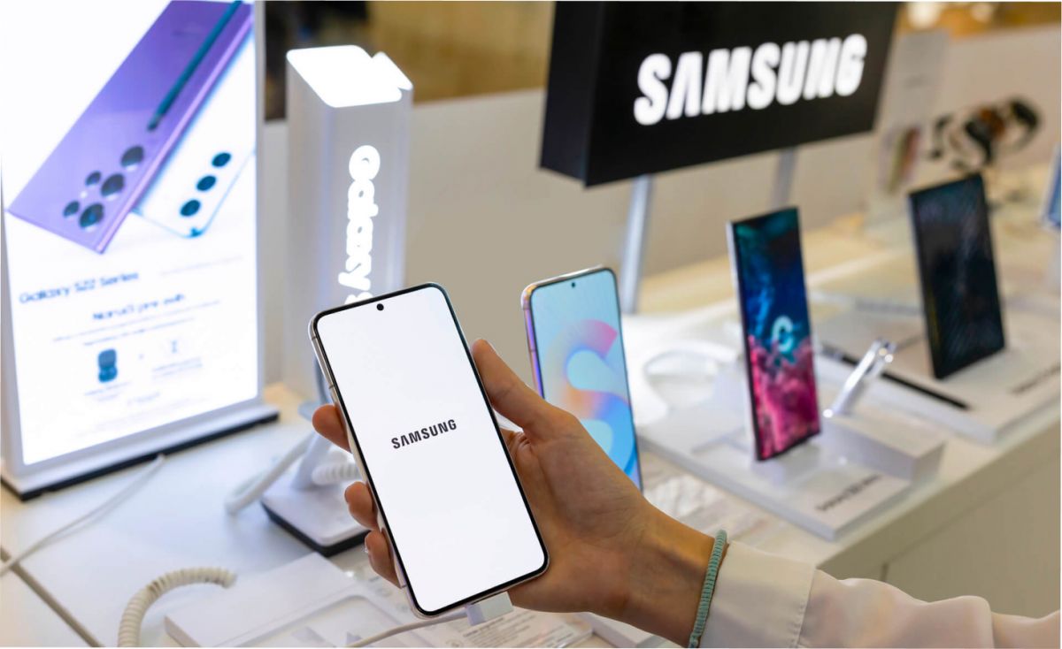 Mano sosteniendo un celular con pantalla encendida y etiquetas de precio