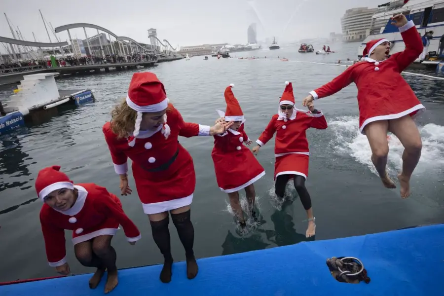 BARCELONA. Nadadores disfrazados de Santa Claus se lanzan al agua para iniciar la carrera Copa Nadal, que parte de la Rambla de Mar.