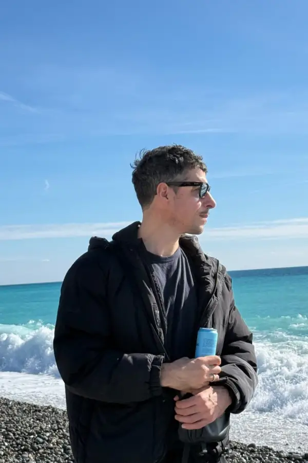 Esteban Lamothe posa rente al mar turquesa de la Costa Azul con gafas de sol y look abrigado total black. 