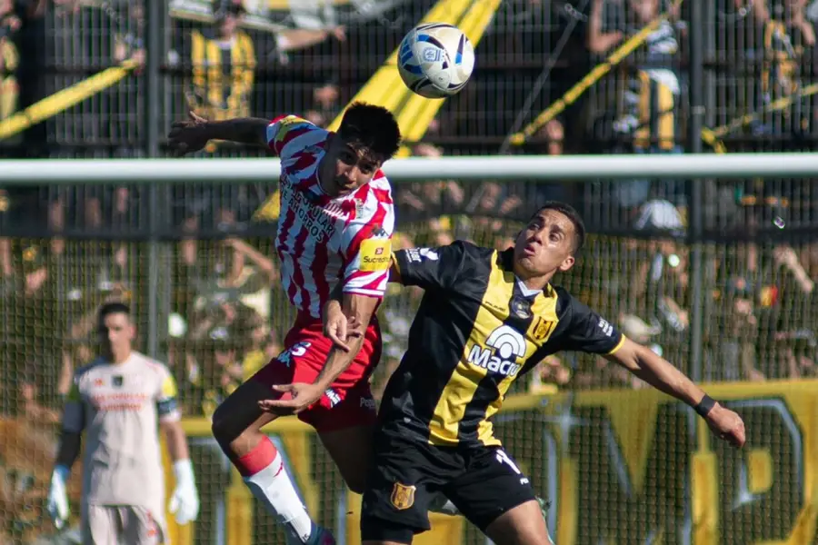 LUCHA AÉREA. Laureano Rodríguez intenta rechazar un balón ante la carga del volante Nicolás Barrientos.