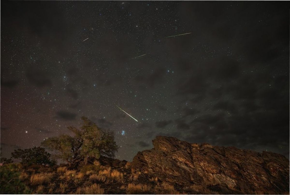 En 2024, meteoros de la lluvia de meteoros de las Perseidas surcaban un cielo parcialmente nublado sobre el Bosque Nacional Inyo en Bishop, California. A la izquierda de la imagen se aprecia un resplandor rosado de aurora boreal, y a la derecha, un ligero resplandor verdoso. La galaxia de Andrómeda aparece en la parte superior, ligeramente a la izquierda del centro. NASA/Preston Dyches