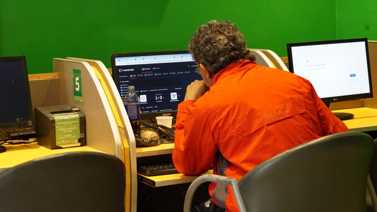 APUESTAS. Un apostador sigue desde una de las terminales de Pálpitos los resultados deportivos en una de las pantallas disponibles en el local.