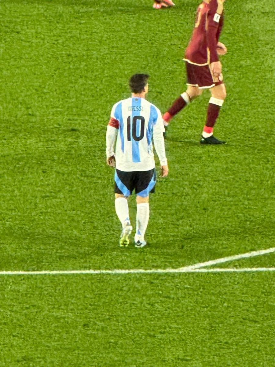 DESPEDIDA. Lionel Messi camina por el campo de juego durante el partido ante Venezuela, mientras un futbolista del seleccionado visitante aparece detrás suyo.