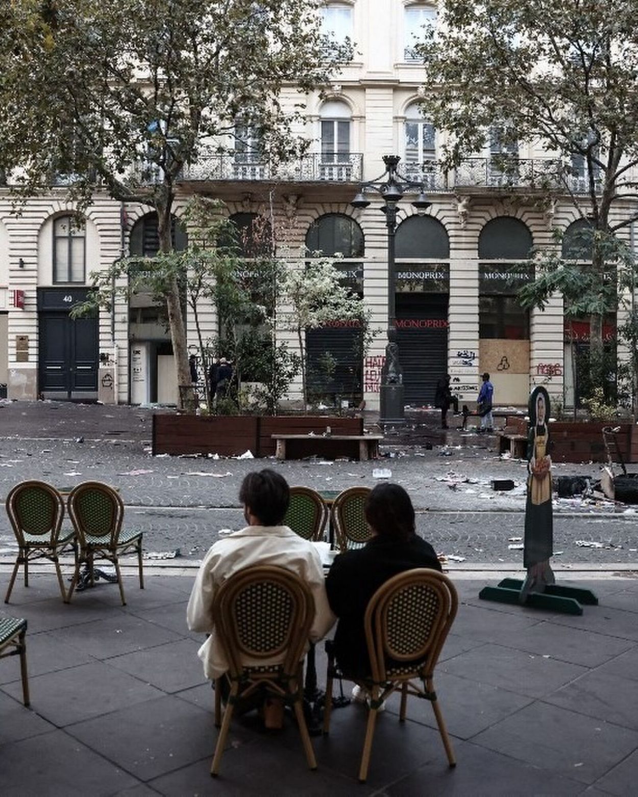 EN MARSELLA. Dos clientes sentados en la vereda de un café, frente a una calle cubierta de escombros, un día después de las protestas.